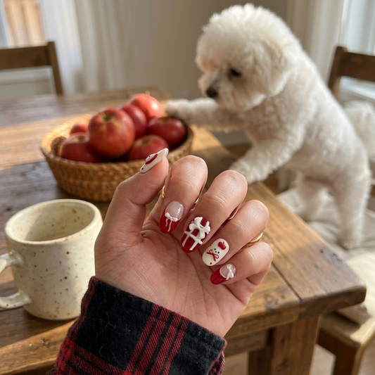 MYOB Nails Apple Pup press-on nails featuring red plaid patterns, cute puppy art, and apple designs, held by a person with an apple mug and a white Bichon dog in a cozy home setting.