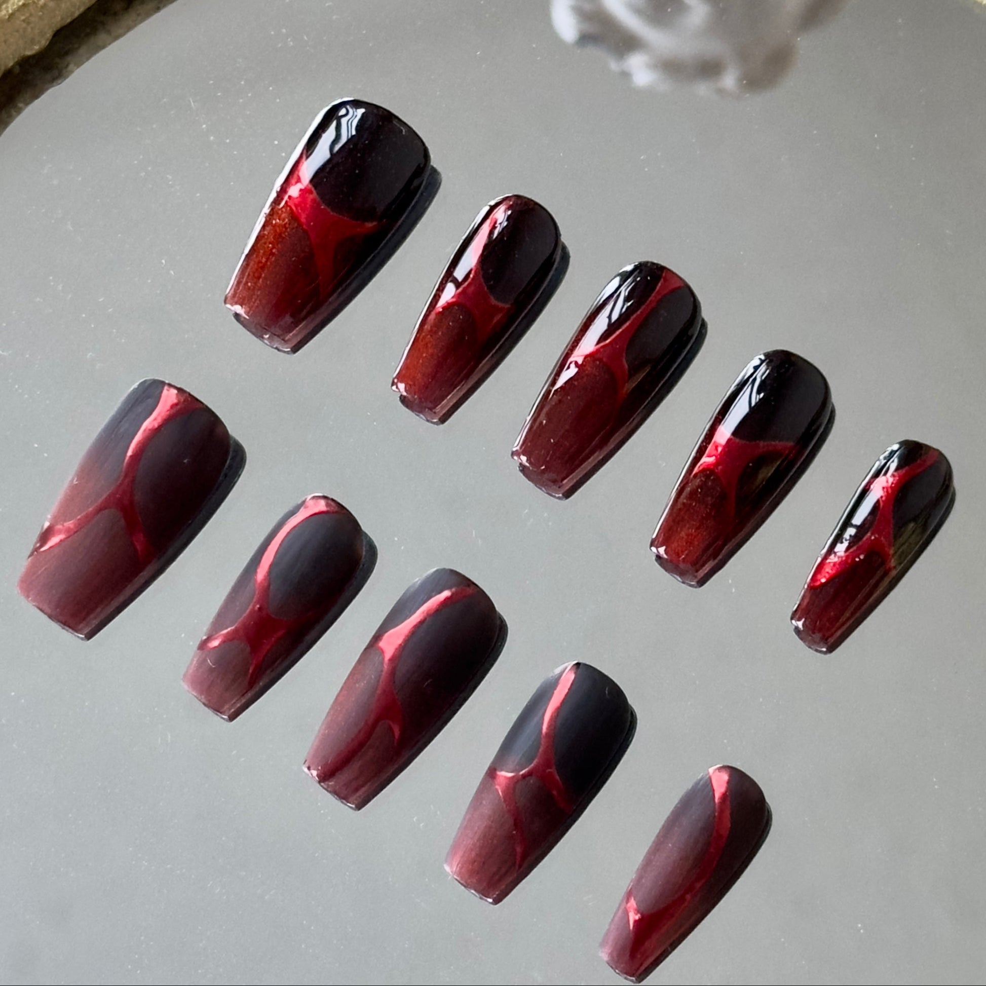 Detailed side view showing the seamless black-to-red ombre transition from the nail root.