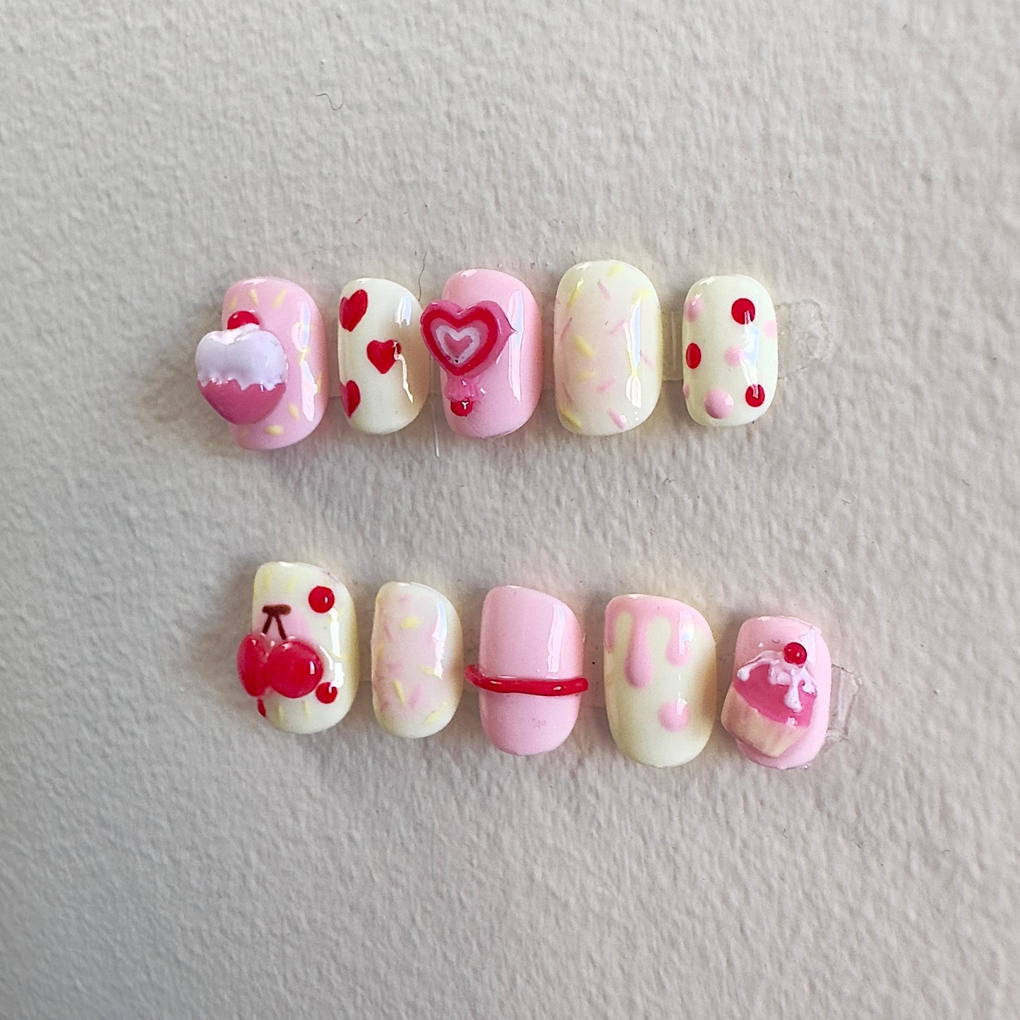 Side view highlighting the textured 3D candy elements and playful heart-shaped lollipop designs.