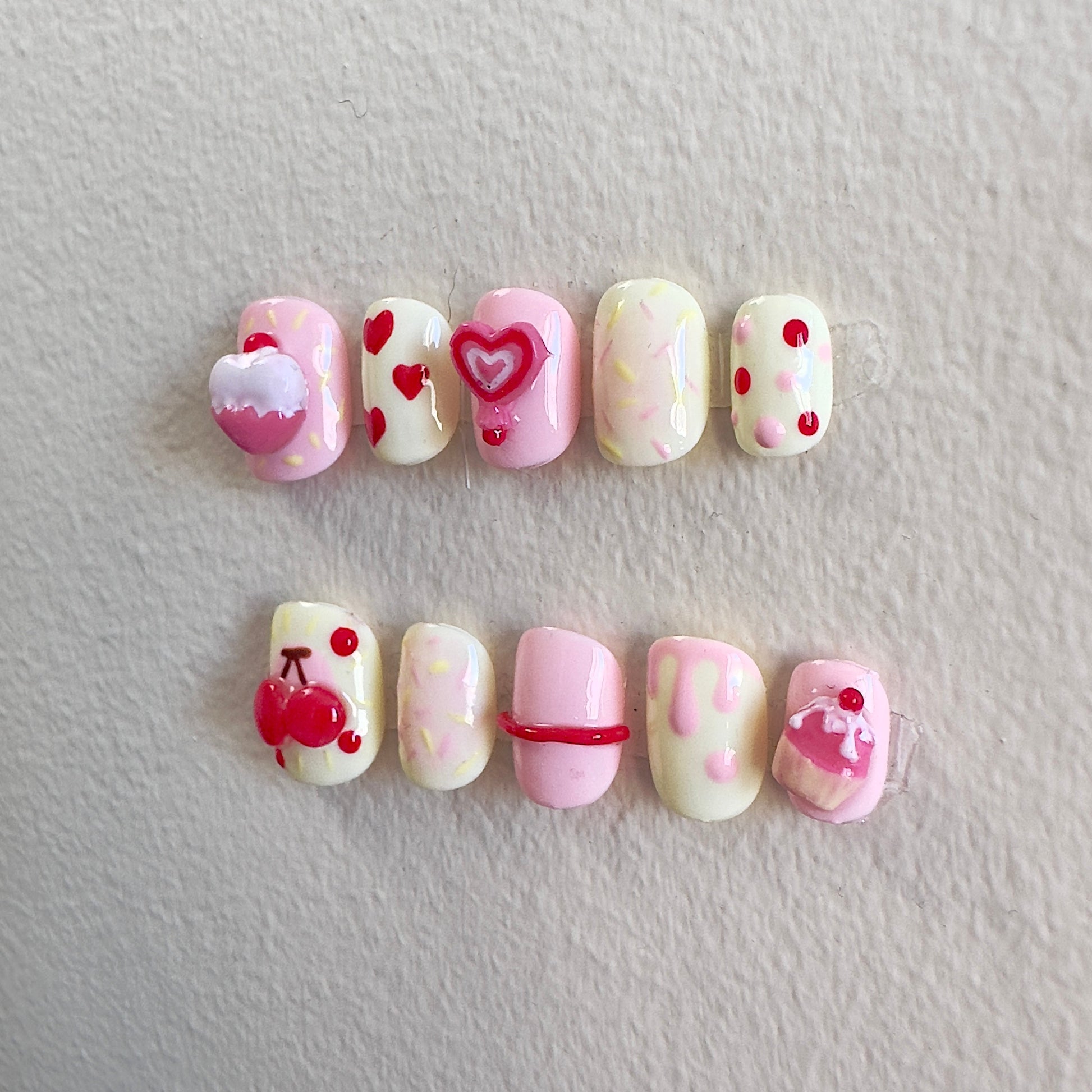 Side view highlighting the textured 3D candy elements and playful heart-shaped lollipop designs.