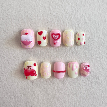 Front view of Cherry Cake nails showing the soft pink and pale yellow base with vibrant 3D charms.