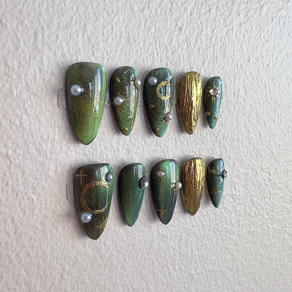 Detailed shot of the metallic gold chrome moon and elegant pearl embellishments on a cat-eye base.