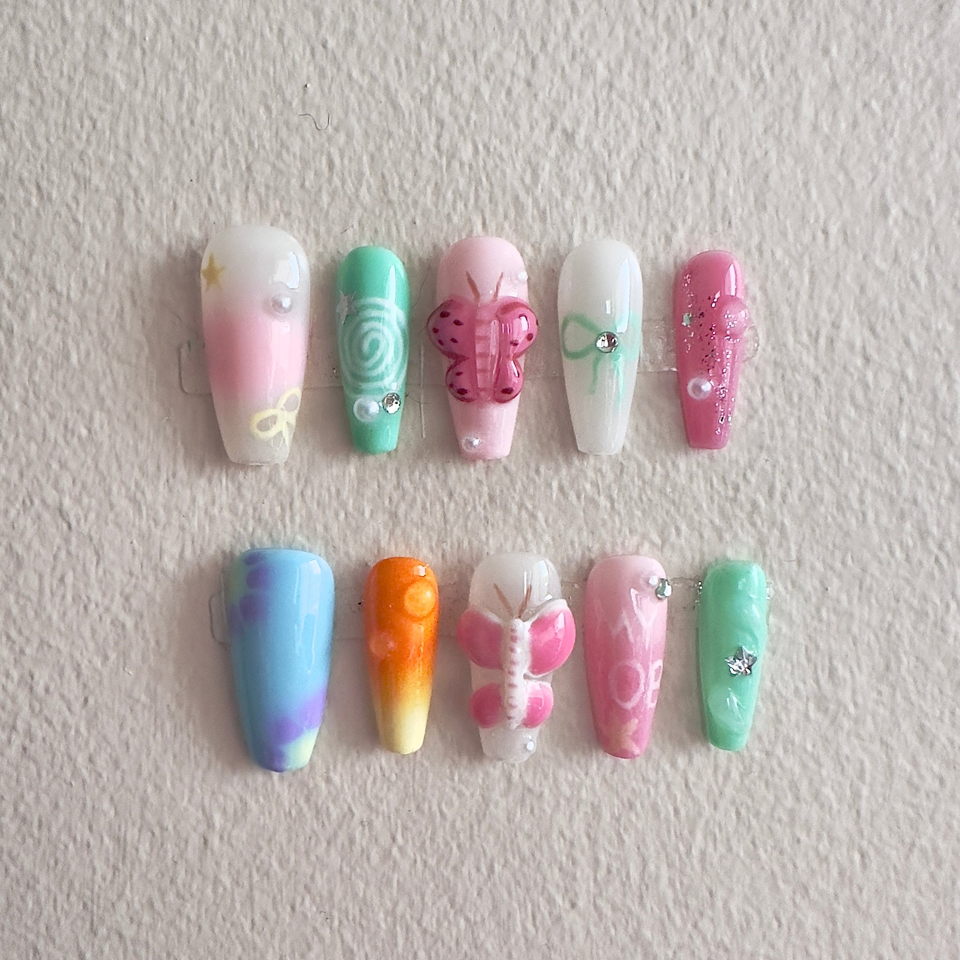 Front view of Fairytale nails showing colorful gradients, shimmering glitters, and hand-painted MYOB lettering.