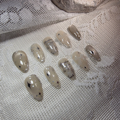 Wide angle shot from the left, displaying the full flow of silver starbursts and metallic outlines across the nails.