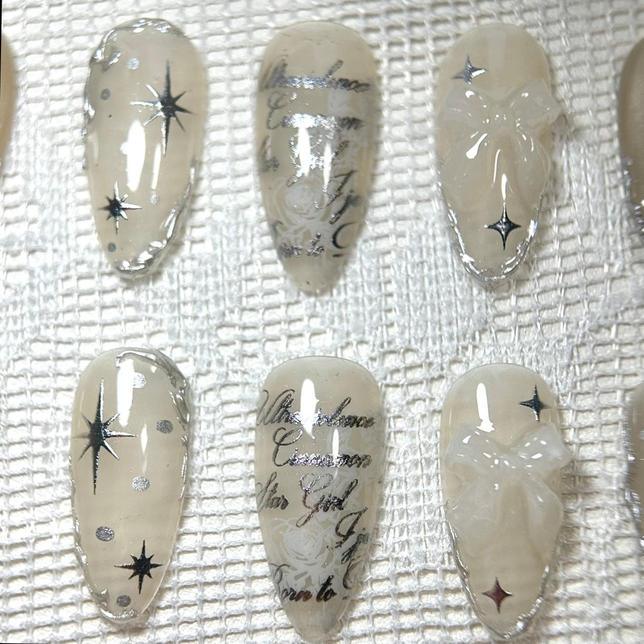 Precision macro capture of the center nails, featuring the silver metallic script over a subtle white rose pattern.
