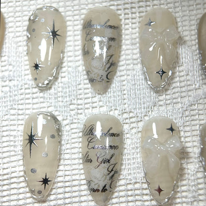 Precision macro capture of the center nails, featuring the silver metallic script over a subtle white rose pattern.
