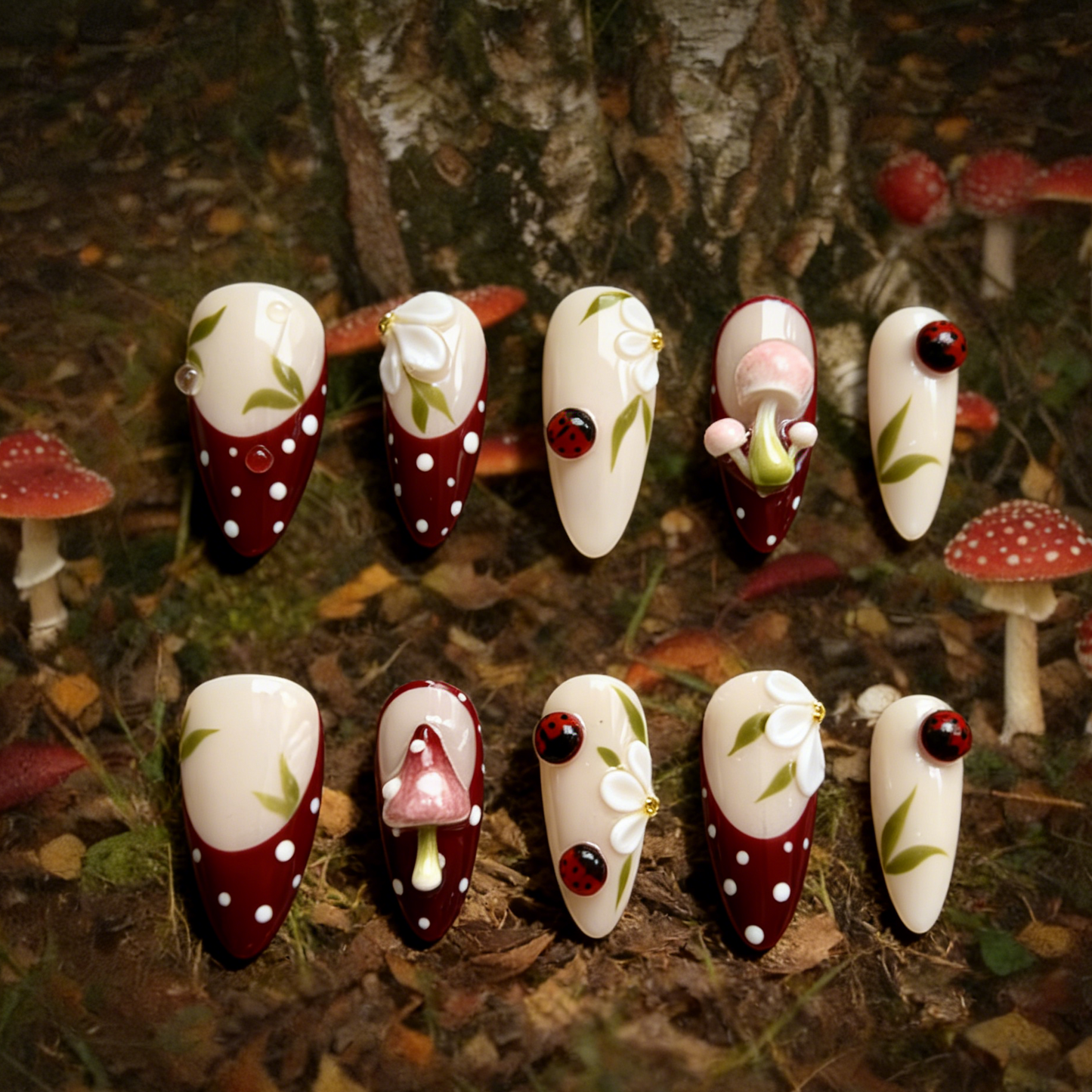 A Glimpse of the Forest press-on nails by MYOB Nails featuring deep red french tips with 3D mushrooms and ladybugs.