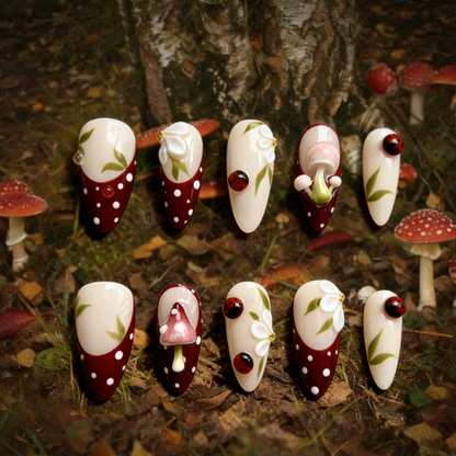 A Glimpse of the Forest press-on nails by MYOB Nails featuring deep red french tips with 3D mushrooms and ladybugs.