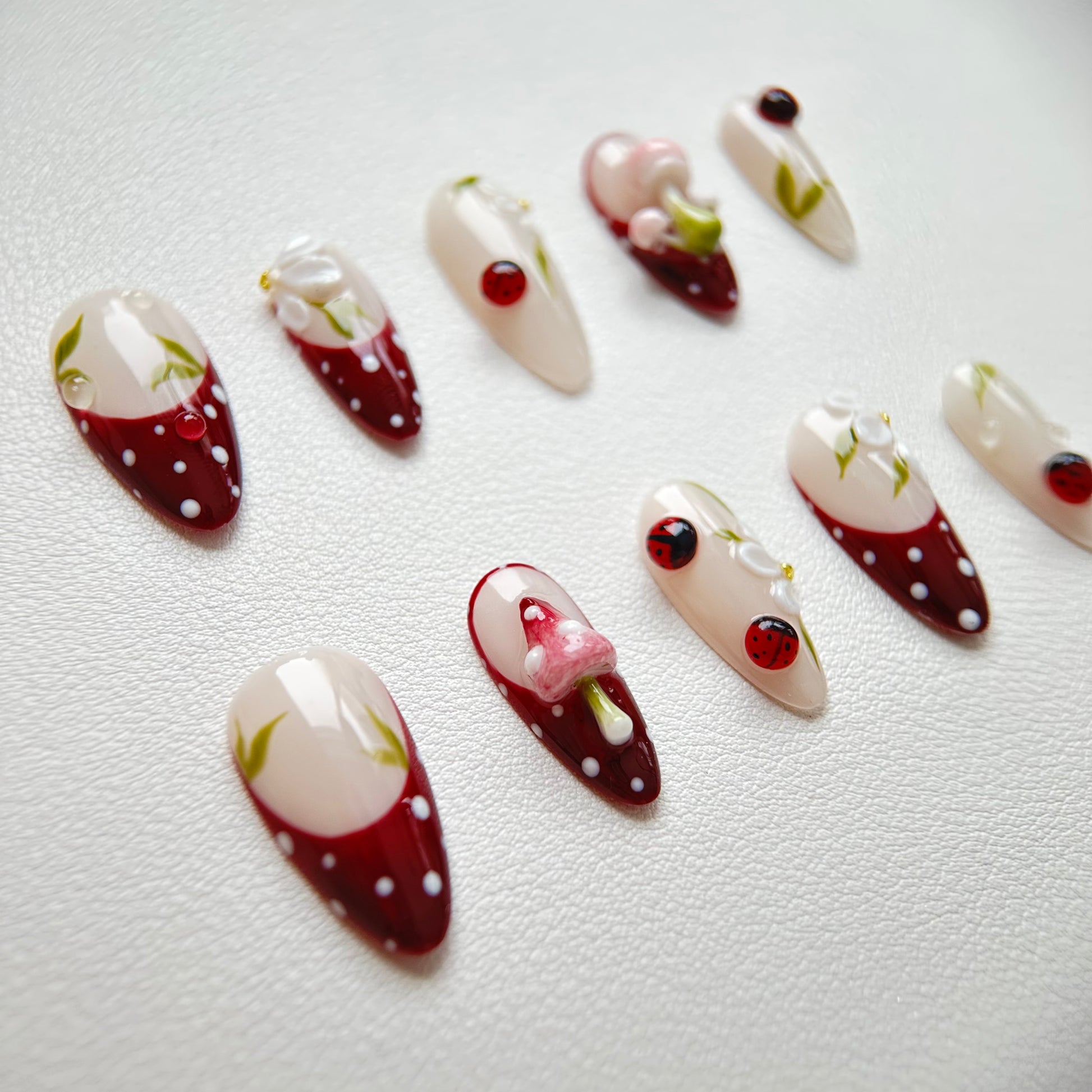 Detailed shot of the realistic 3D pink mushrooms and precise white polka dots on a deep red french base.