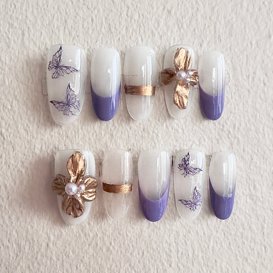 Front view of Gold Lavender nails showcasing purple French tips, golden bands, and pearl-centered floral charms.