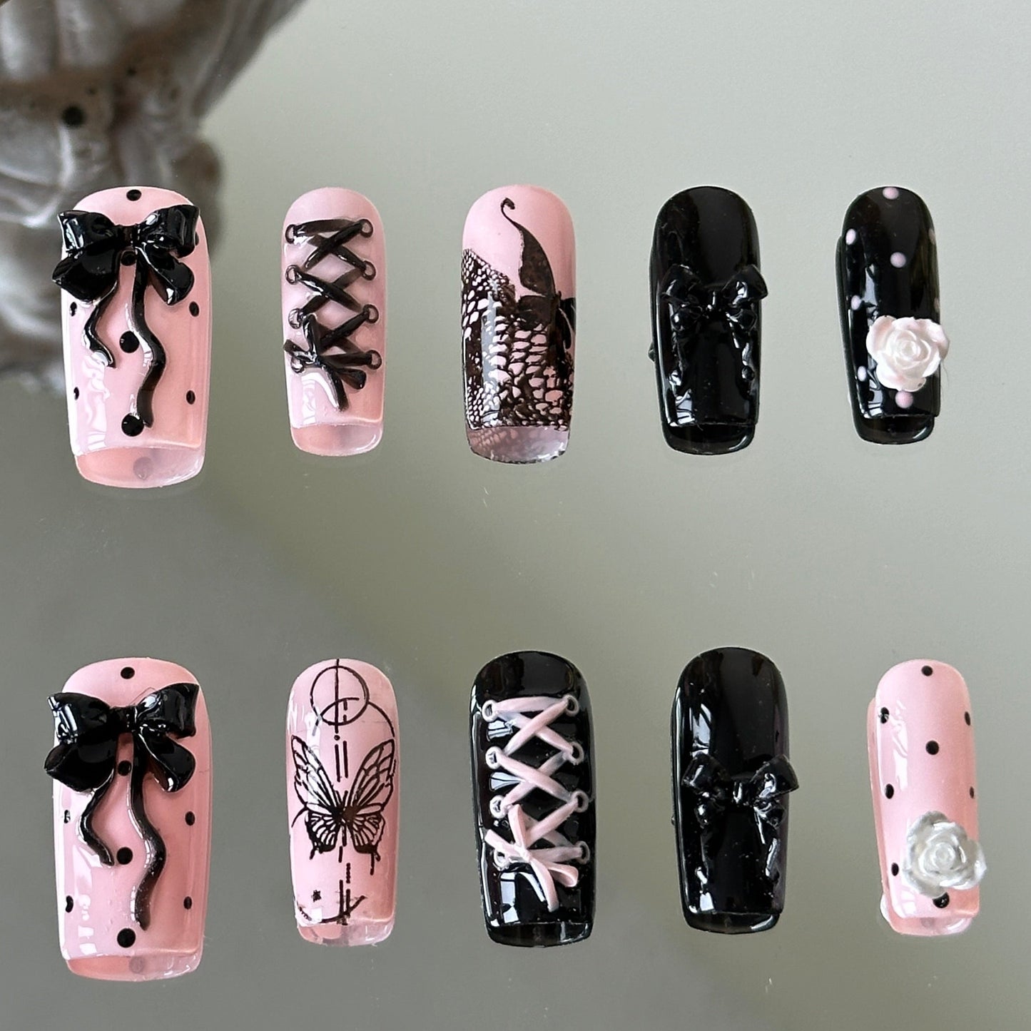 Front view of Gothic Lolita handmade nails with 3D bows, corset lacing, and hand-painted lace butterflies.