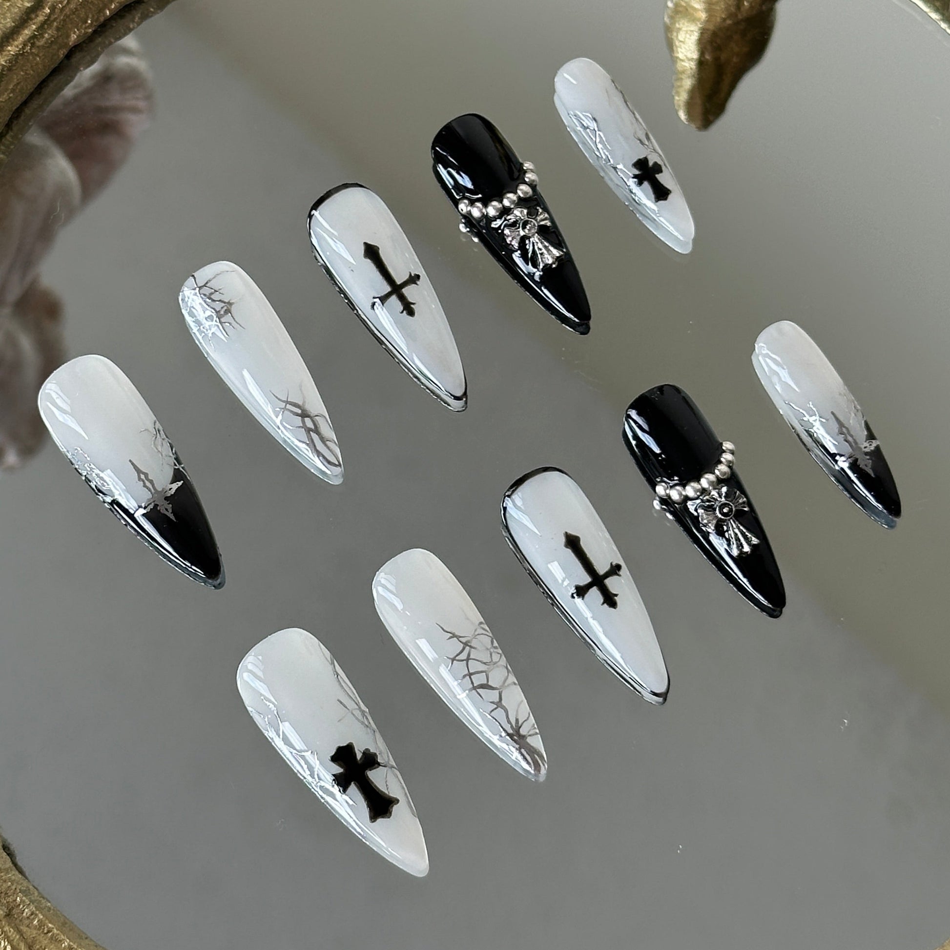 Close-up of the 3D metallic cross and silver steel beads on the ring-finger nail by MYOB Nails.