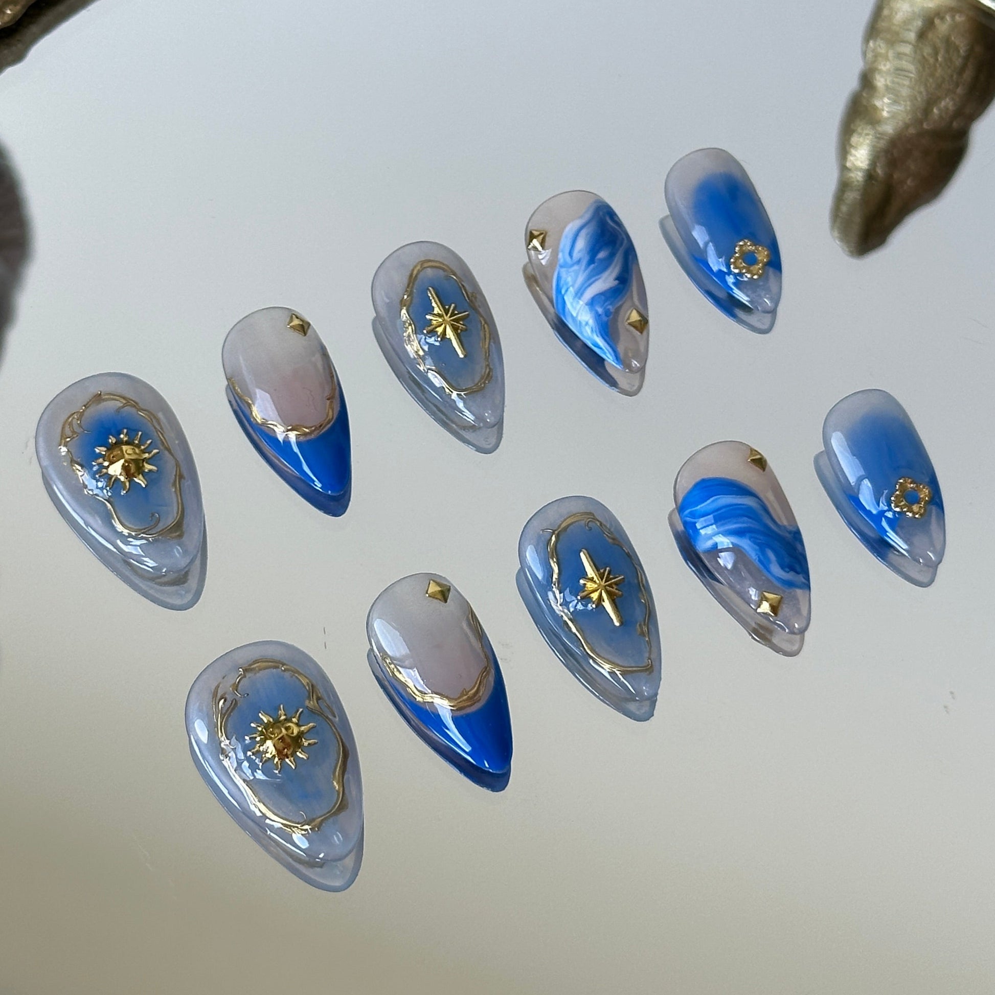 Left side detail of MYOB Nails highlighting the ethereal blue and white watercolor-style smudging on a nude base.