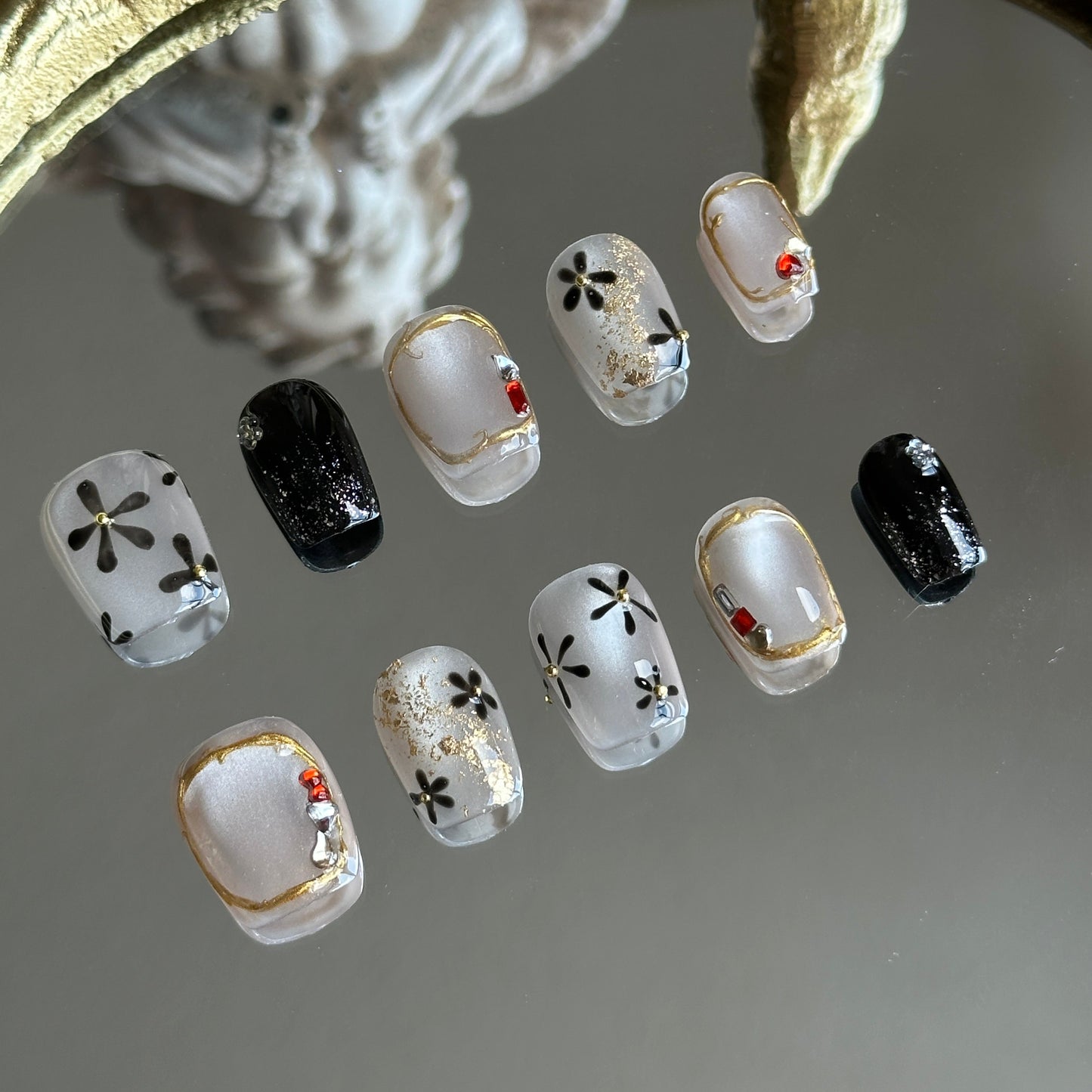 Left side detail of MYOB Nails Moonlit Blossom highlighting silver cat-eye, black floral motifs, and tiny gold steel beads.