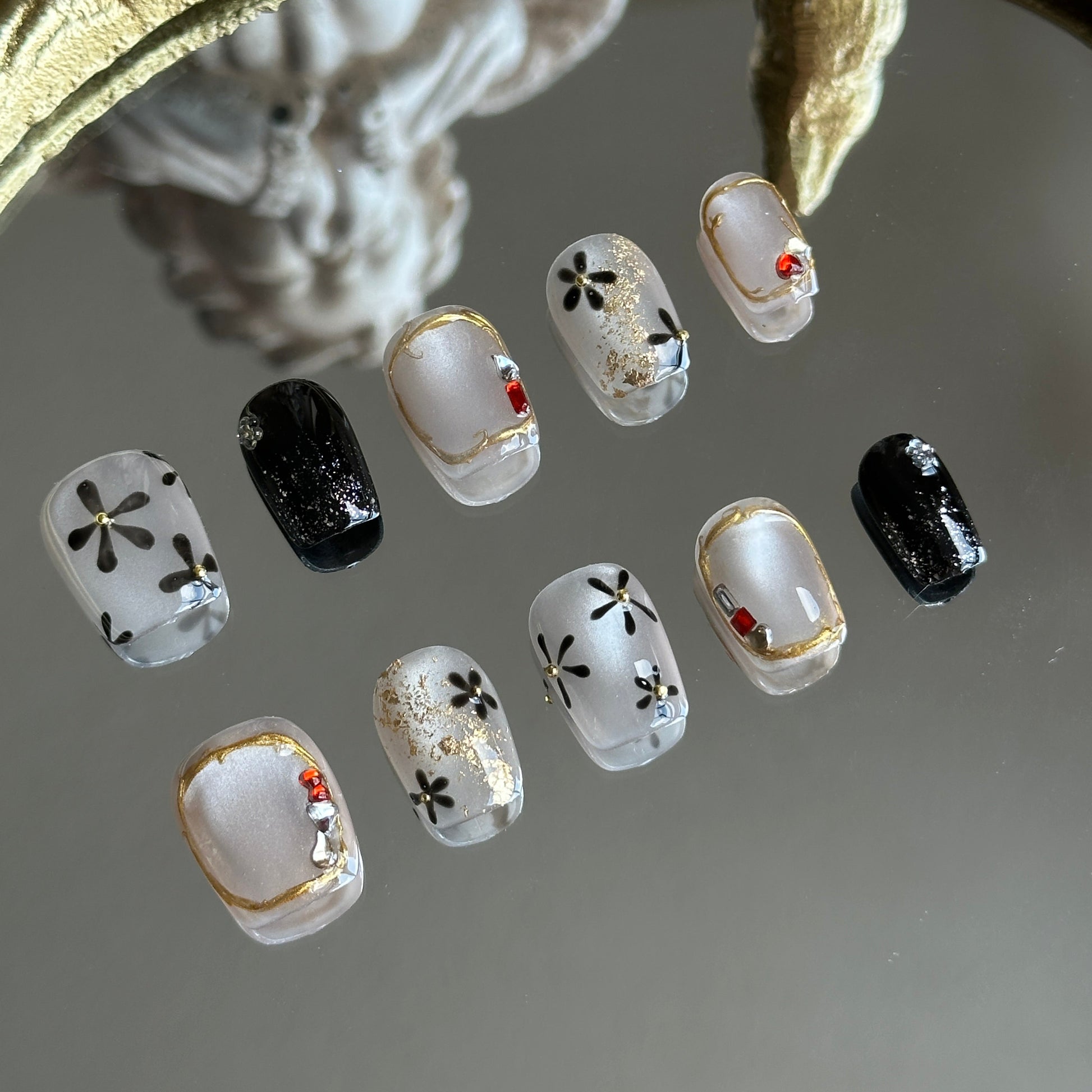 Left side detail of MYOB Nails Moonlit Blossom highlighting silver cat-eye, black floral motifs, and tiny gold steel beads.