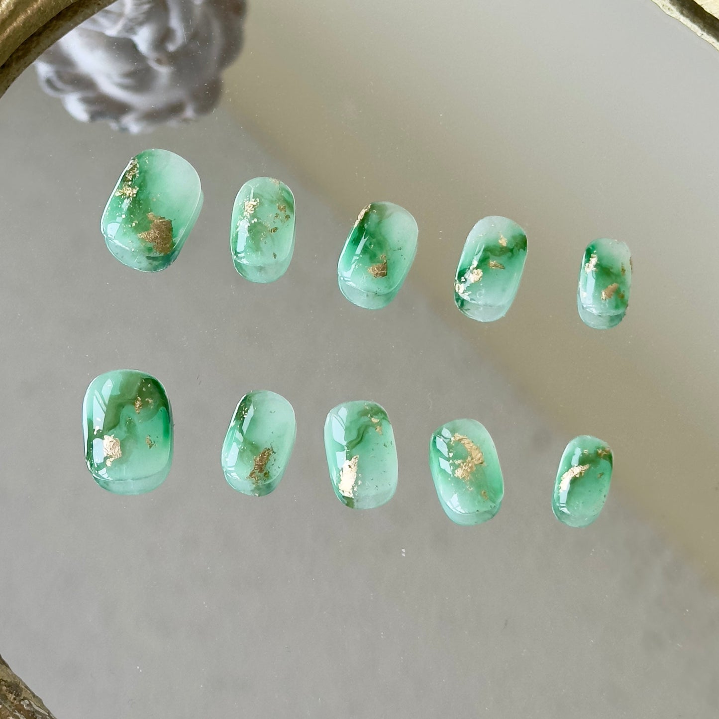Front view of Mossy nails showing the natural diagonal green marbling and luxury gold foil accents.