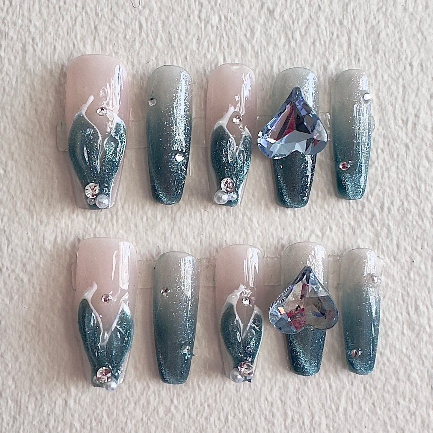 MYOB Nails handcrafted press-on nails with deep blue cat eye gradient effect, featuring shimmering magnetic light, flowing white line art, and a luxury 3D blue heart crystal gem.