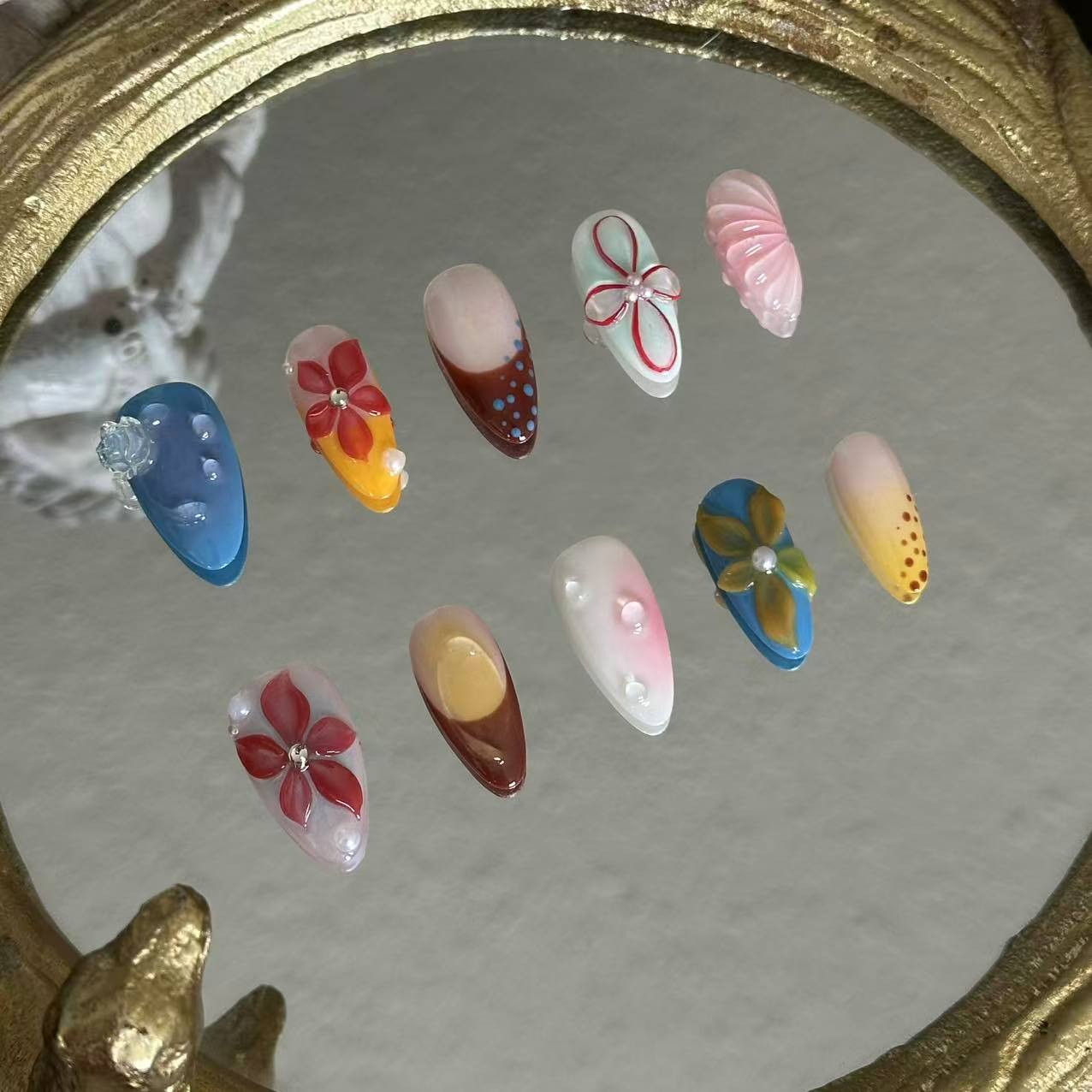 MYOB Nails Ethereal Bloom almond press-on nails, left angle laid atop vintage mirror, showcases sculpted floral depth, nail thickness and handcrafted dimensional flower textures