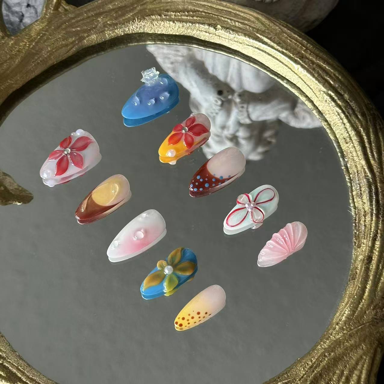 MYOB Nails Ethereal Bloom almond press-on nails, right angle shot on ornate mirror, displays natural nail curvature, pearl inlays and nuanced pastel spring colour gradients