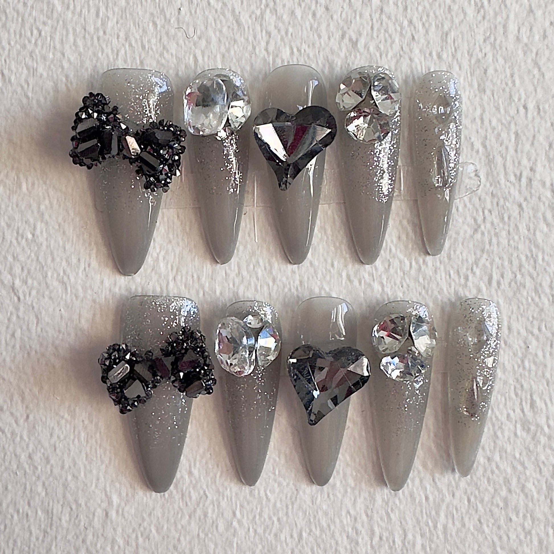 MYOB Nails grey shimmer press-ons with large 3D black bows and dark heart crystals.