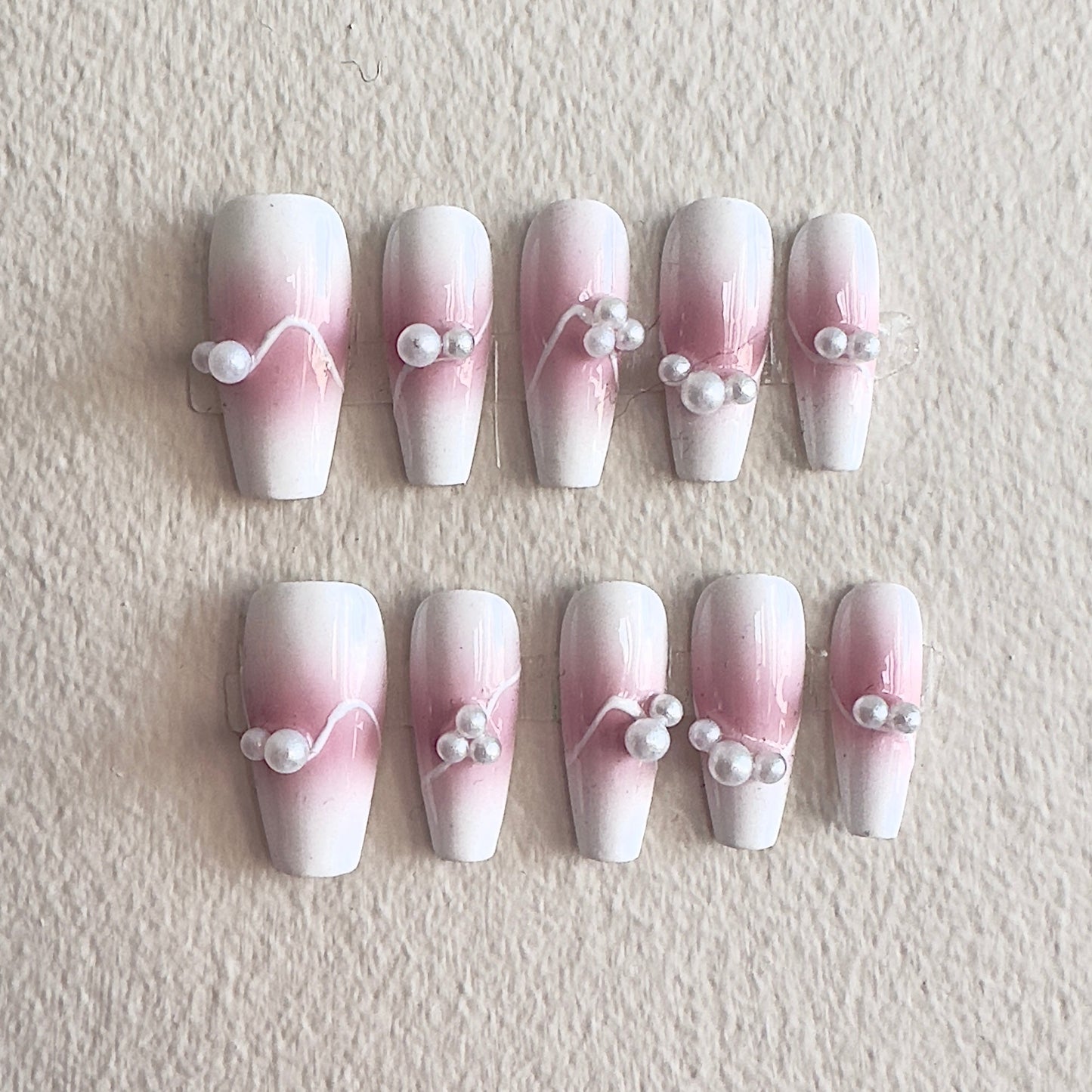 MYOB Nails elegant pink and white ombre press-on nails featuring delicate flowing white line art and minimalist pearl accents, perfect for a sophisticated look.