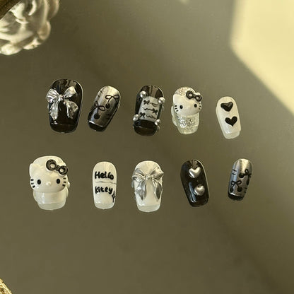 MYOB Nails Y2K style press-on nails in black and white, featuring 3D cute cartoon cat charms and silver metallic ribbons.