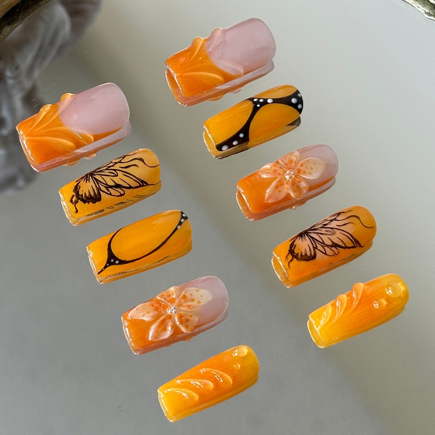 Side view showcasing the 3D sculpted flowers, transparent water drops, and elegant orange French tips.