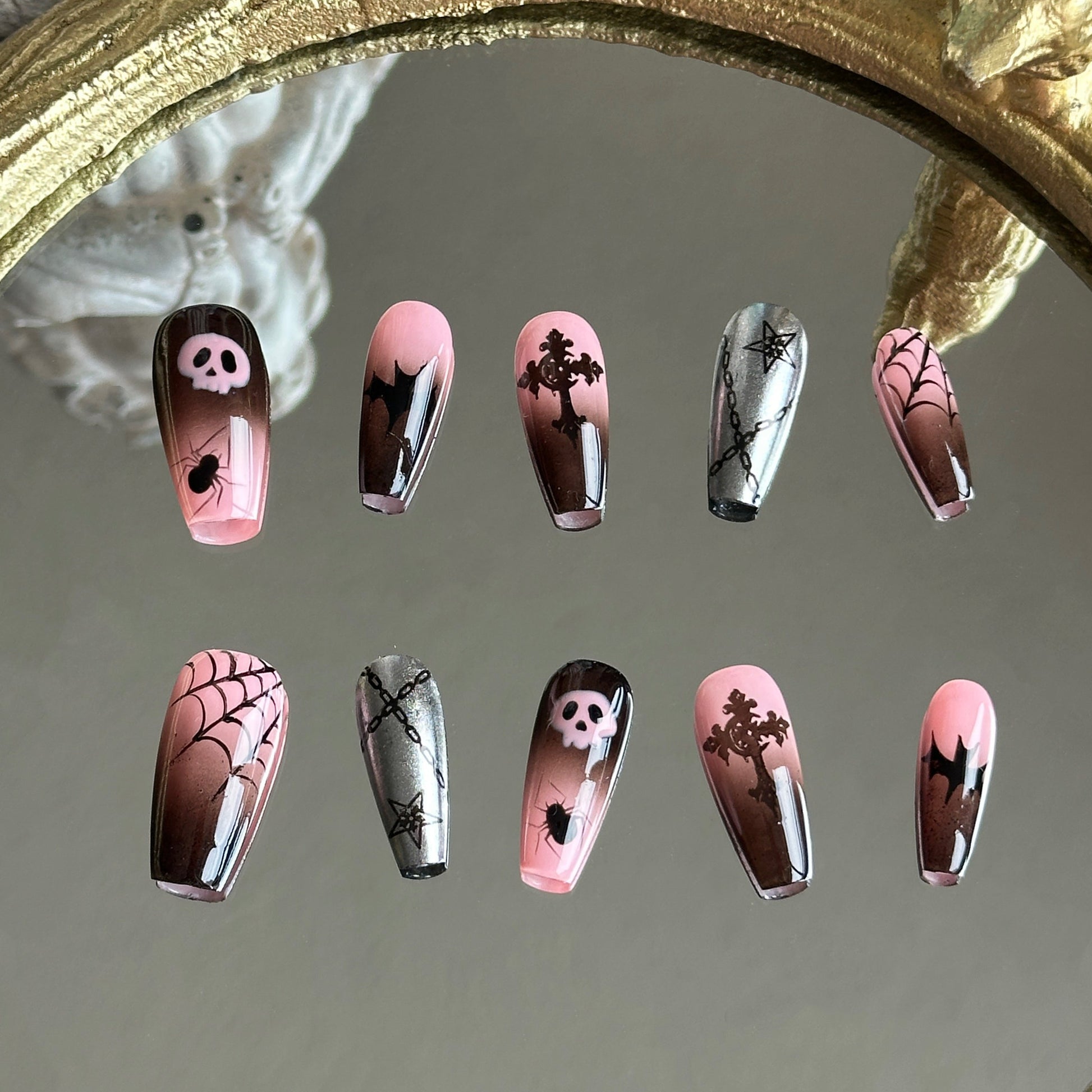 Front view of Pink Abyss handmade press-on nails by MYOB Nails featuring pink-black ombre, skulls, bats, and spiderwebs.