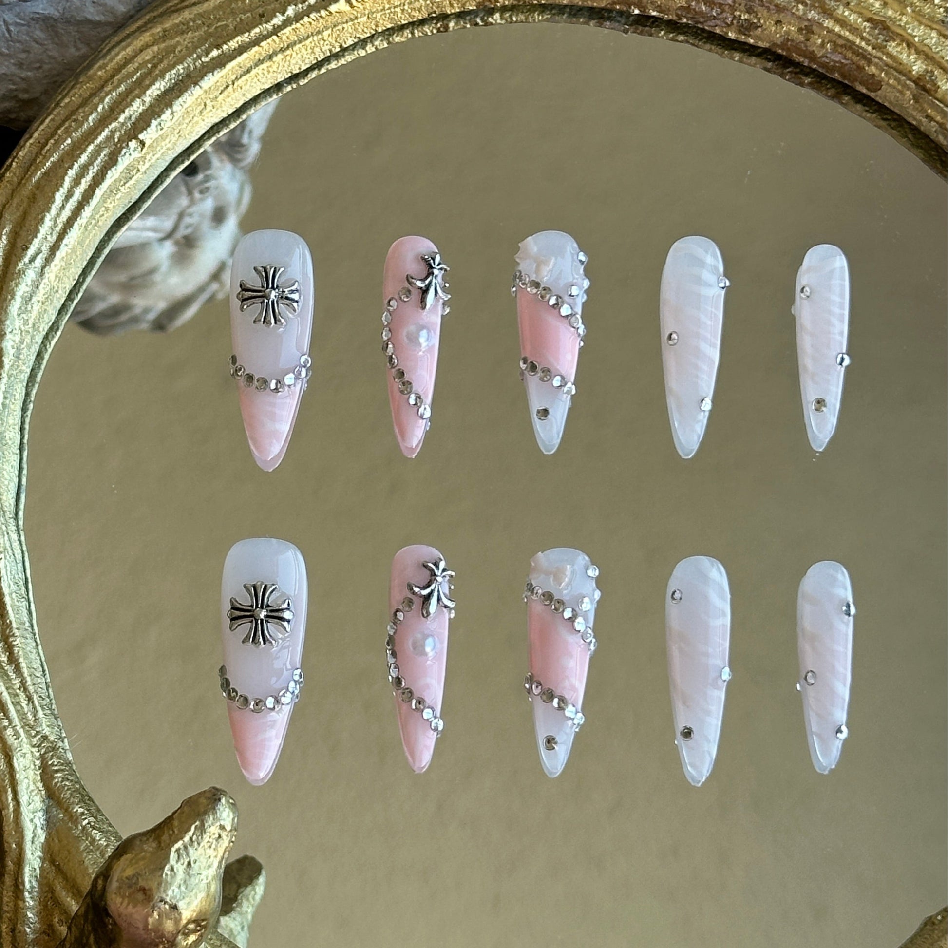 Front view of Princess Rebel handmade press-on nails by MYOB Nails featuring pink and white marble base with silver crosses and chain accents.