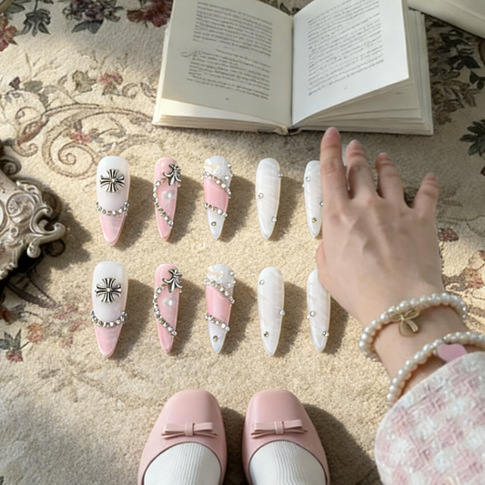 Princess Rebel press-on nails by MYOB Nails, featuring a pink and white palette with silver chrome heart and cross charms, rhinestones, and pearl accents.