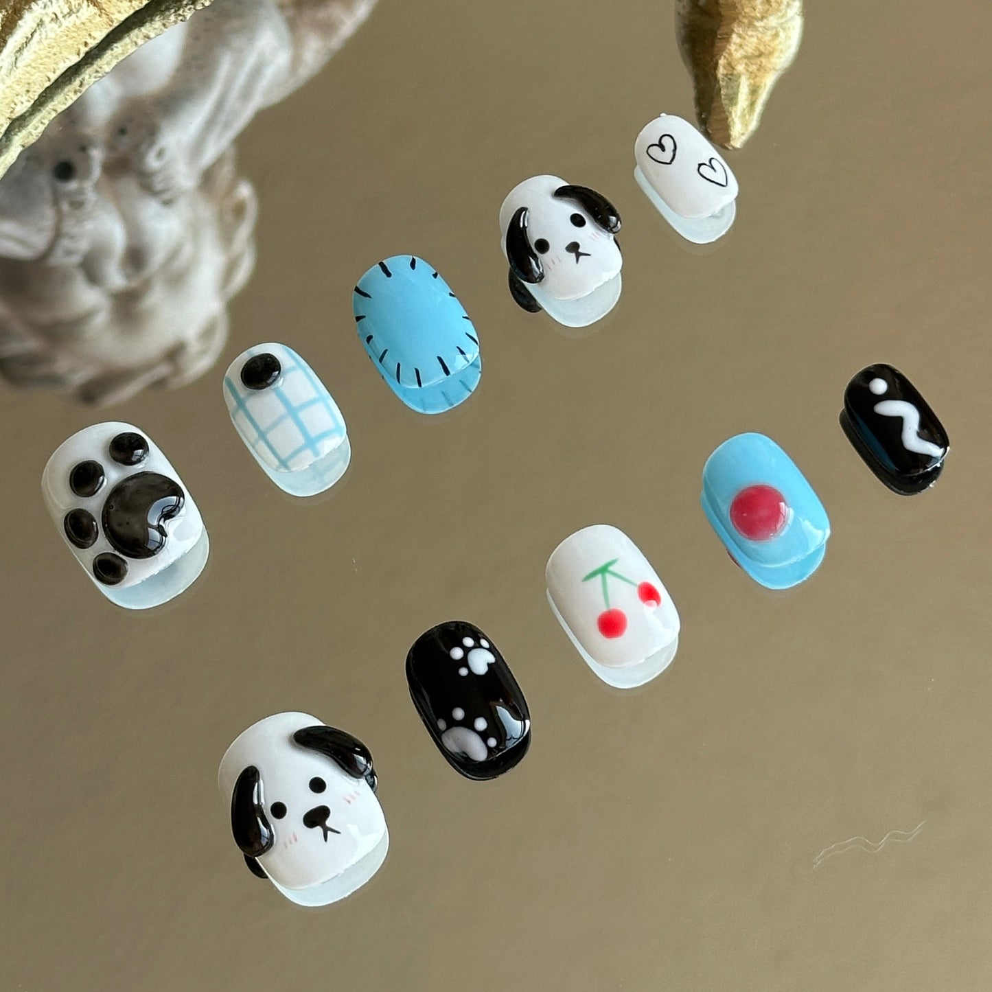 Left side detail of MYOB Nails Puppy Love set highlighting the textured 3D puppy paw and bright red cherry motifs.