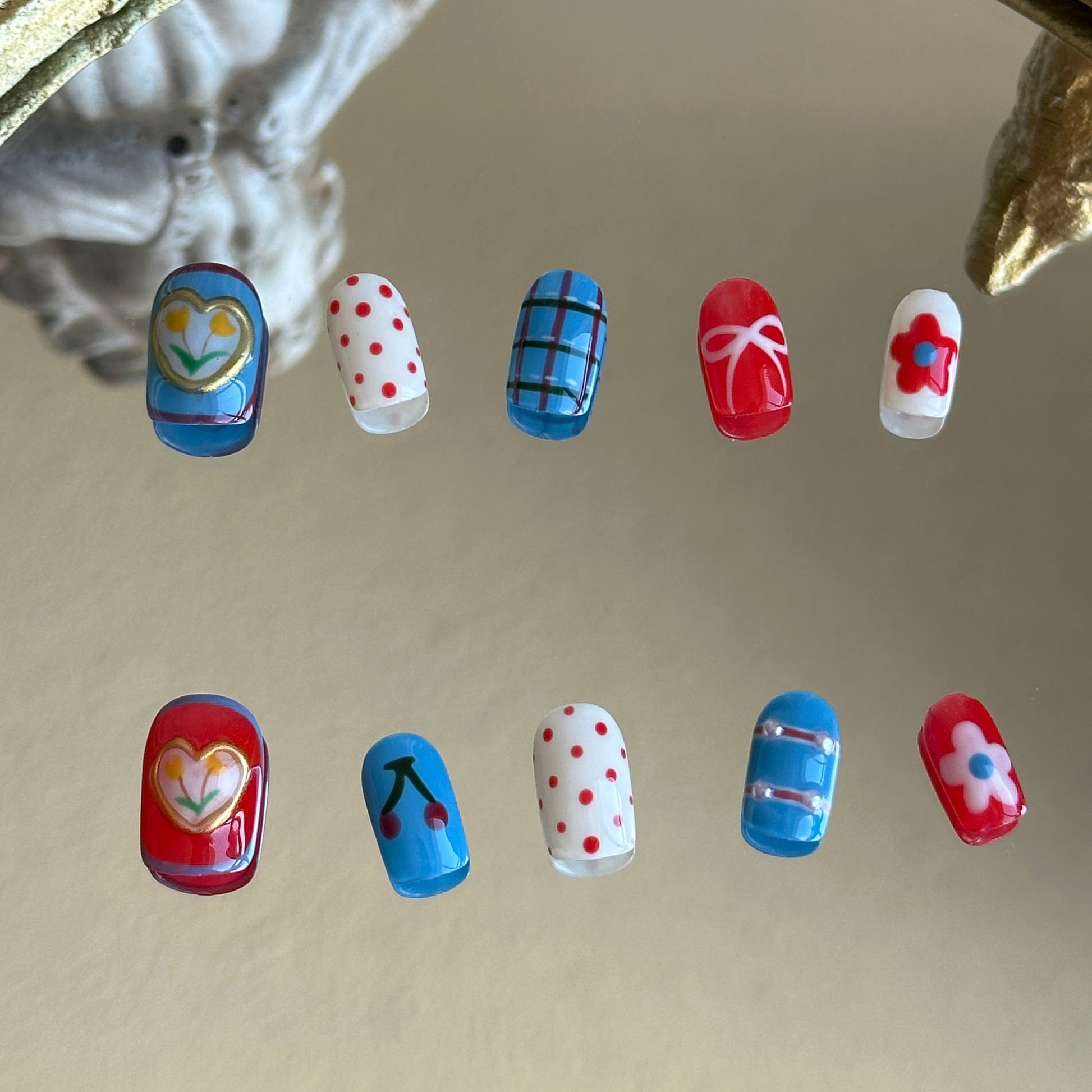 Front view of Retro Bloom handmade nails by MYOB Nails showcasing red and white checkerboard tips with vibrant blue accents.