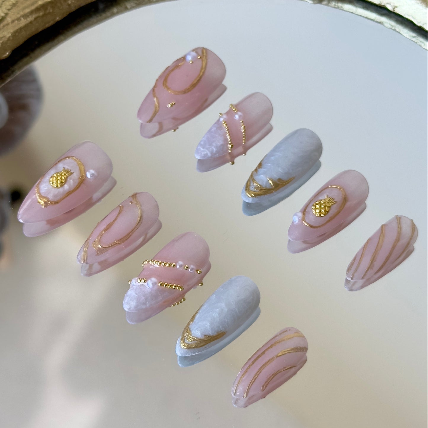 Side view highlighting the fluid gold chrome linework, metallic French borders, and precision-placed pearls.