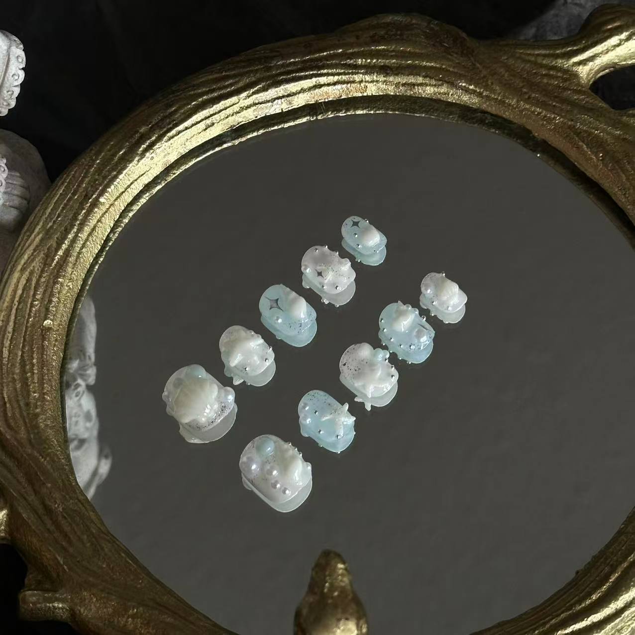 Detailed shot of the oversized 3D white scallop shell and delicate pearl accents on a sparkling blue base.
