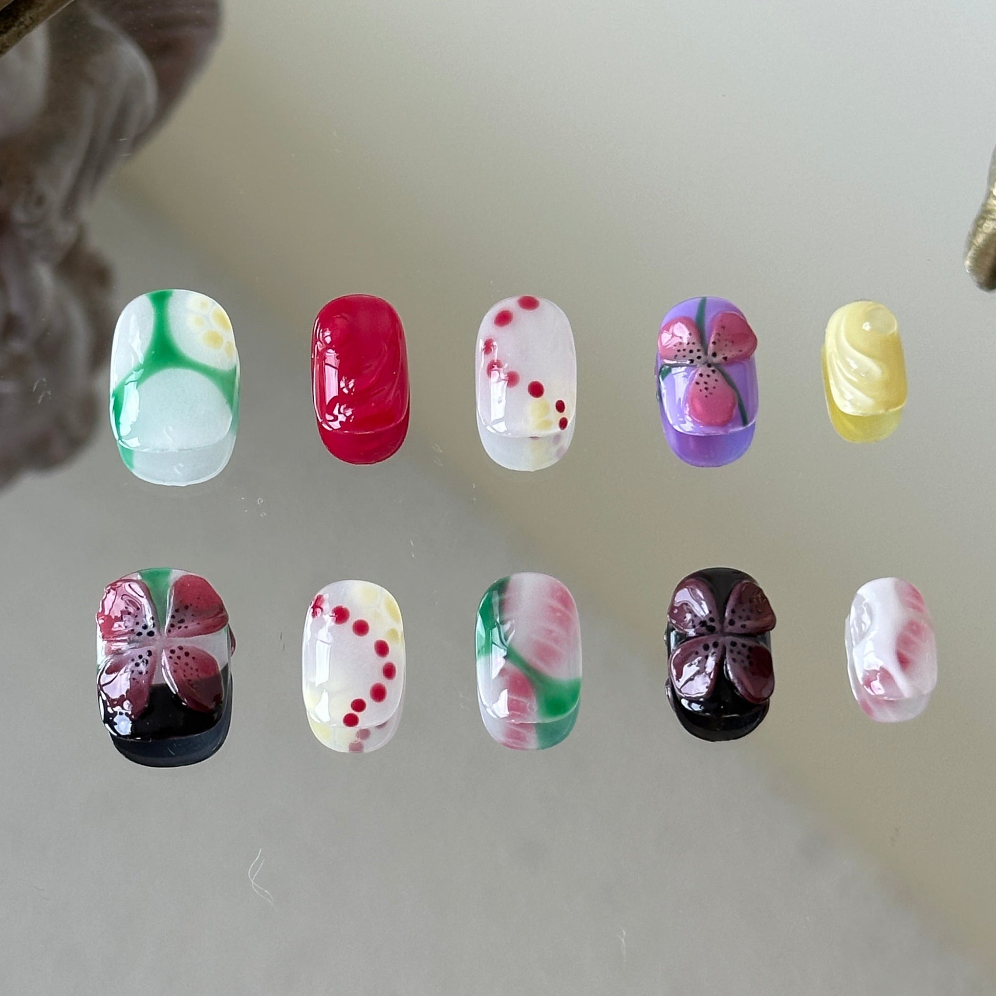 Front view of Tropilush handmade nails with a mix of red dots, 3D florals, and bright summer gradients.