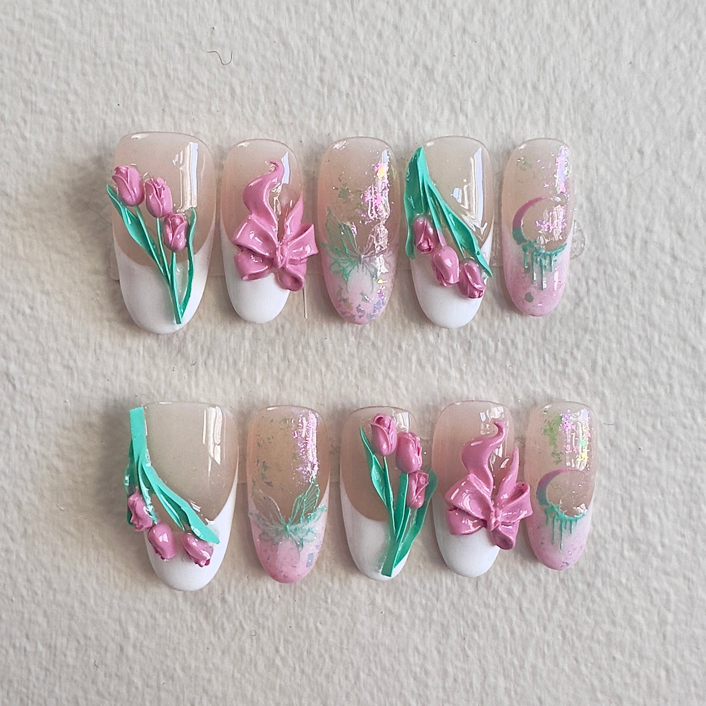 Front view of Tulip Whisper nails showing the sheer nude base, white French tips, and shimmering opal accents.
