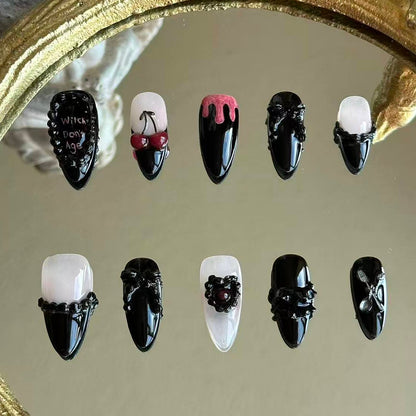Front view of Witches Don't Age handmade press-on nails by MYOB Nails featuring black stiletto base with 3D red cherries and gothic relief.
