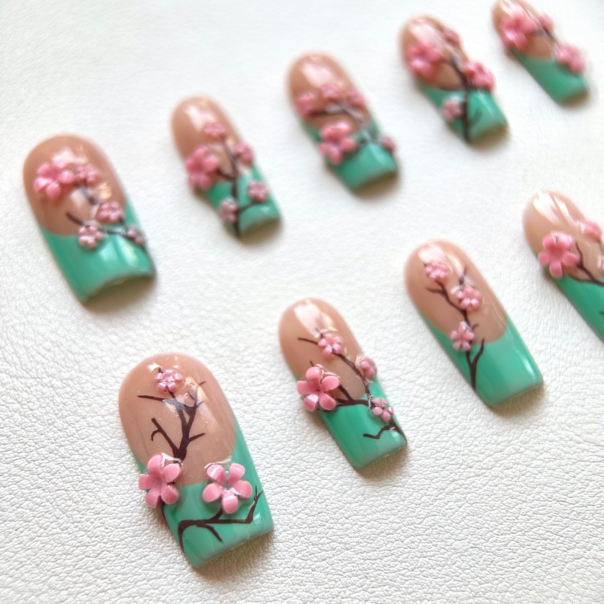 Detailed shot of the multi-dimensional pink cherry blossoms and the smooth teal-to-tan gradient finish.